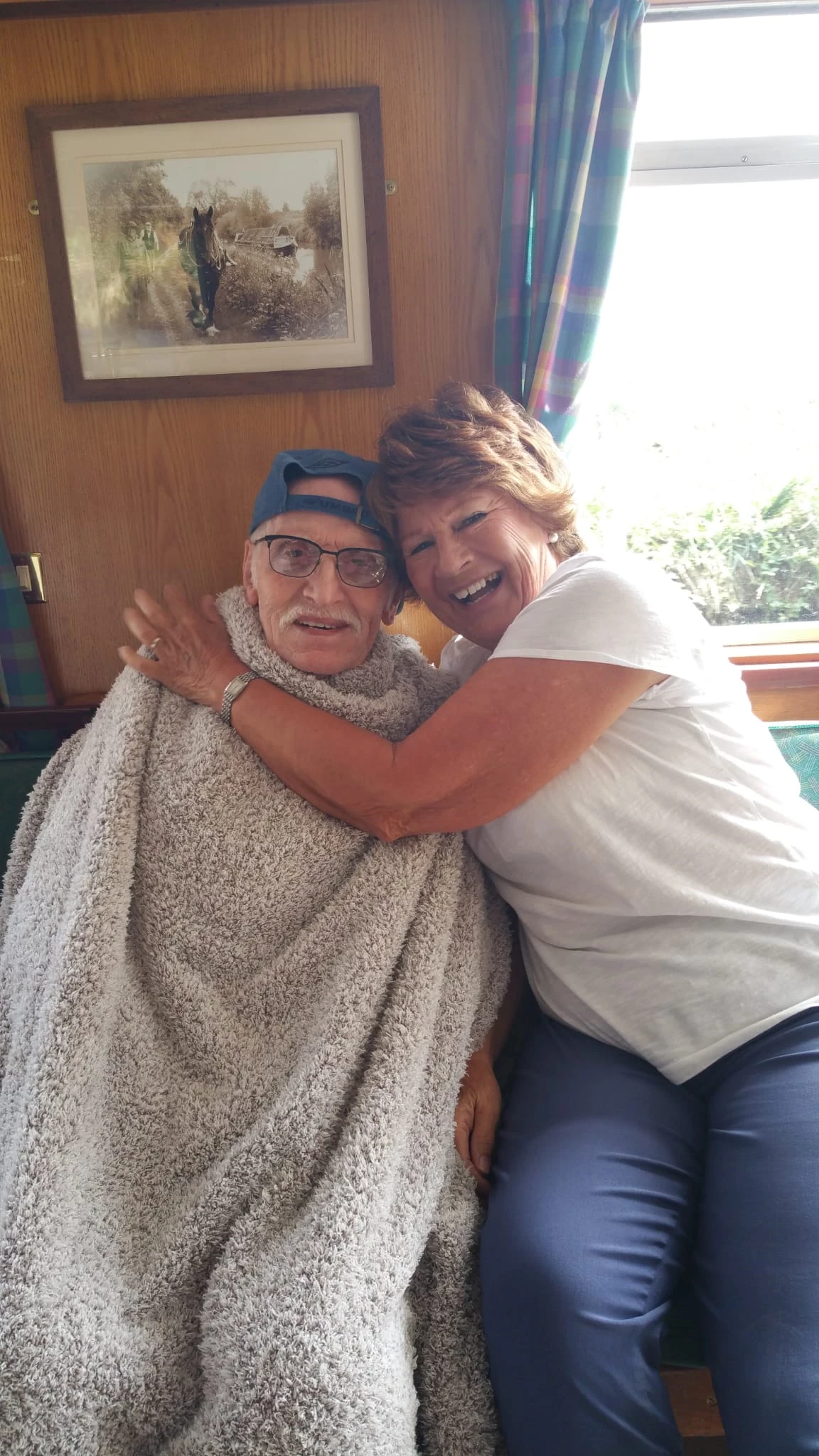 A woman hugging a man with a blanket wrapped round him 