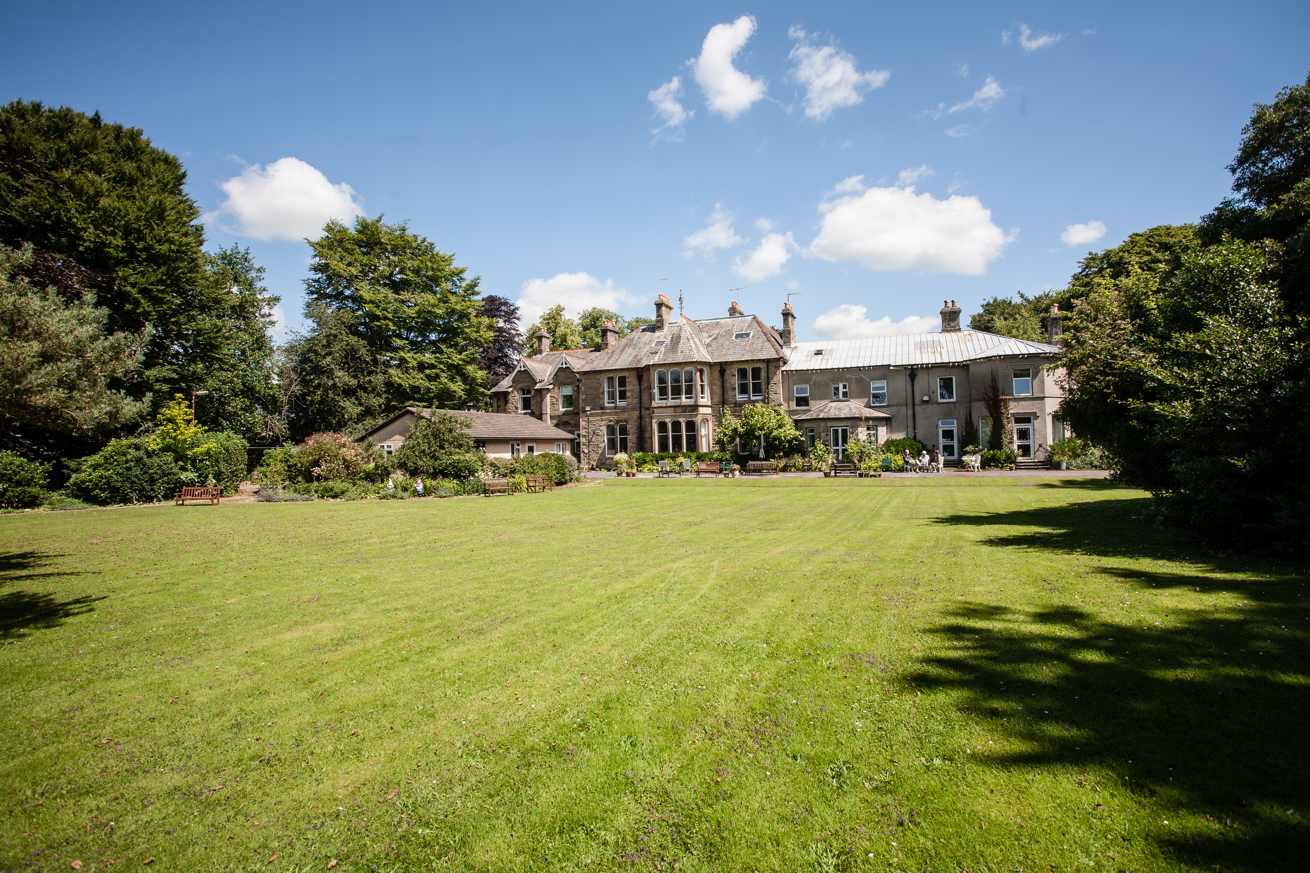 A huge garden with large trees and Cove House in the distance