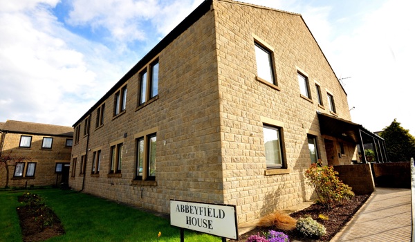 View of the outside of Abbeyfield House with gardens and shrubs