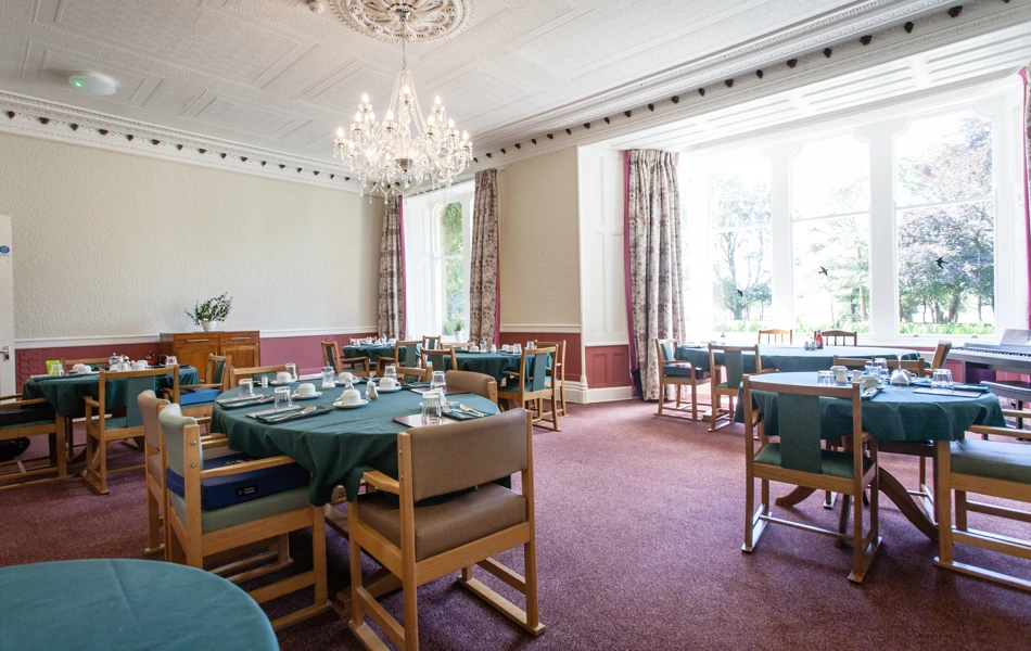 A large dining room with a chandelier and tables set for dinner