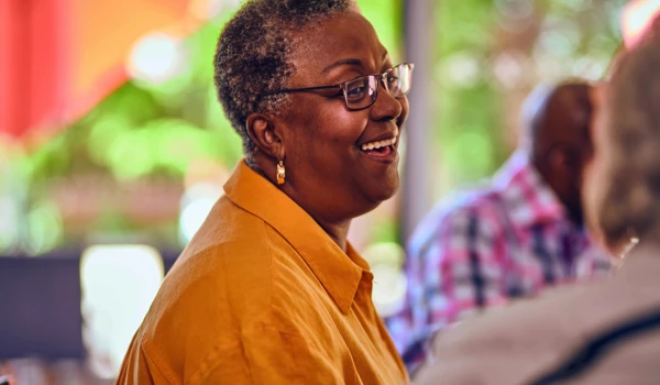 Older Woman Smiling Whilst Sitting With A Group Of People