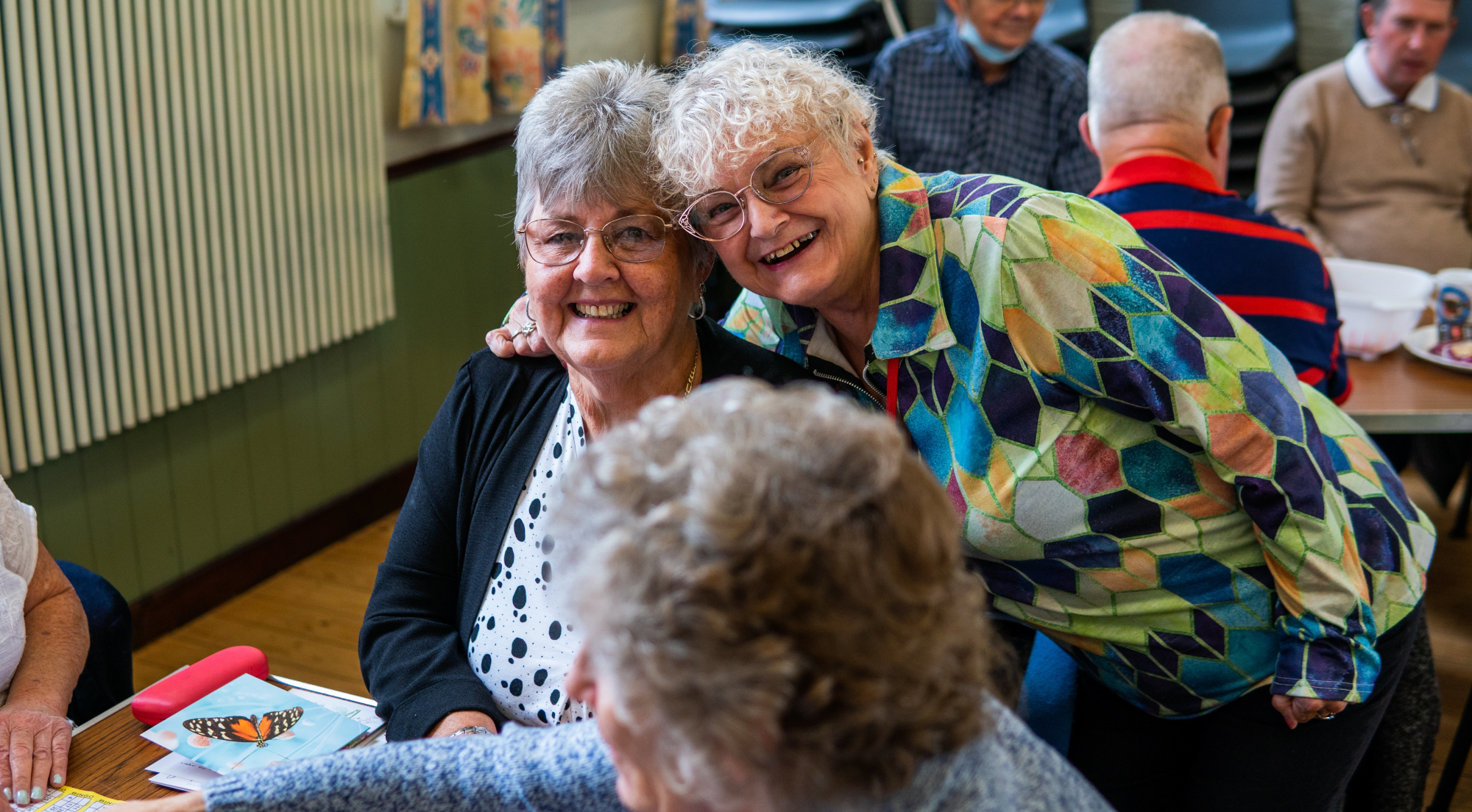 Two Older Women Smiling At Group Activity
