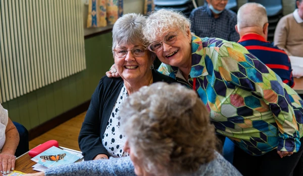 Two Older Women Smiling At Group Activity
