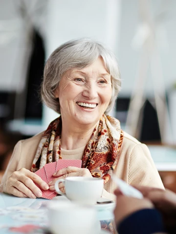 Woman Smiling Whilst Playing Cards At The Table