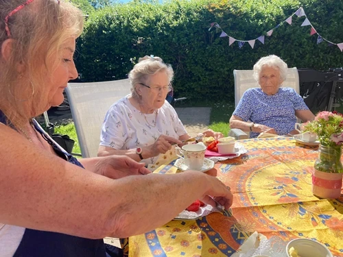 Staff and residents enjoying cake outside