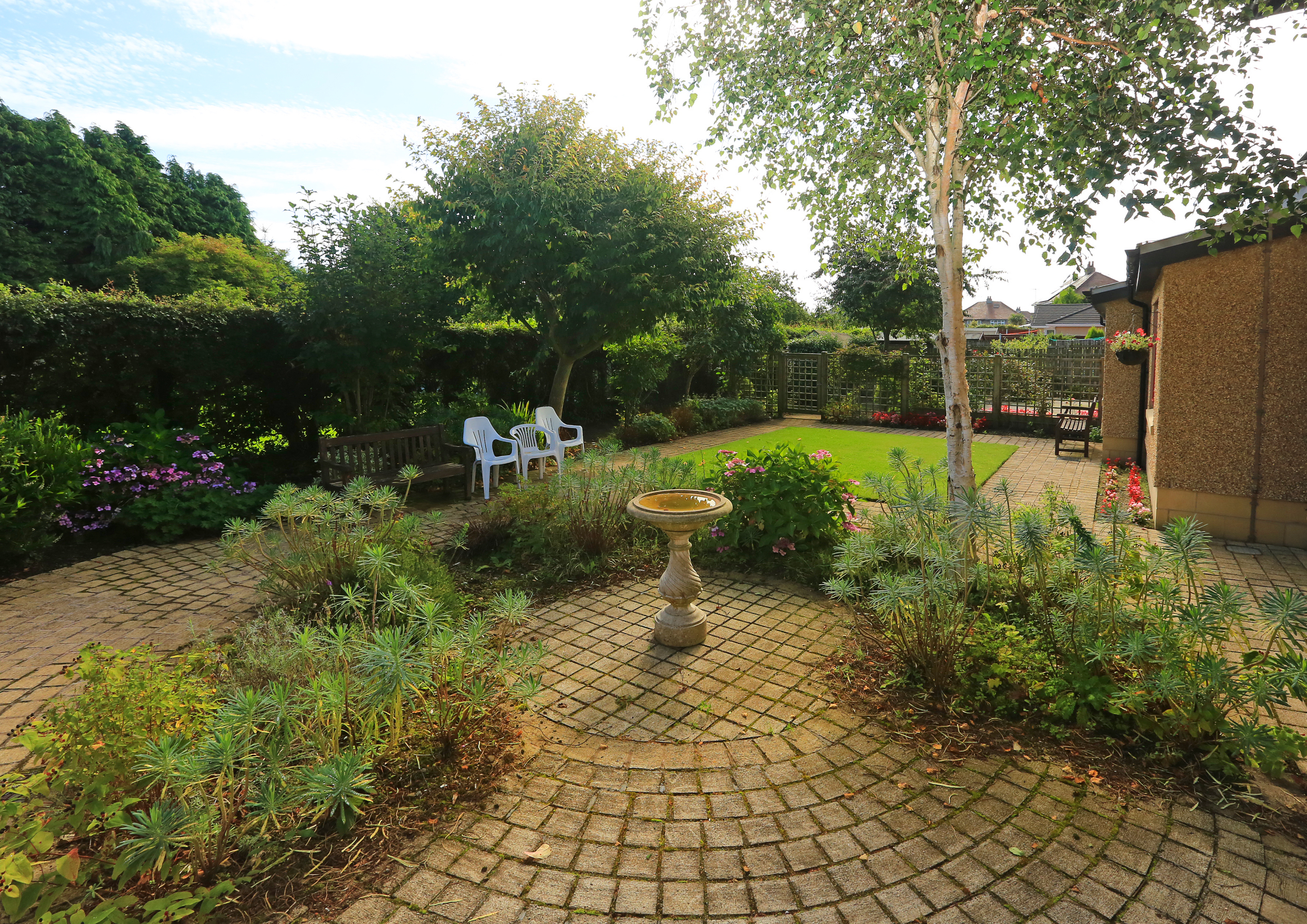 Outside garden area with paved patio and bird bath at Chirnside House