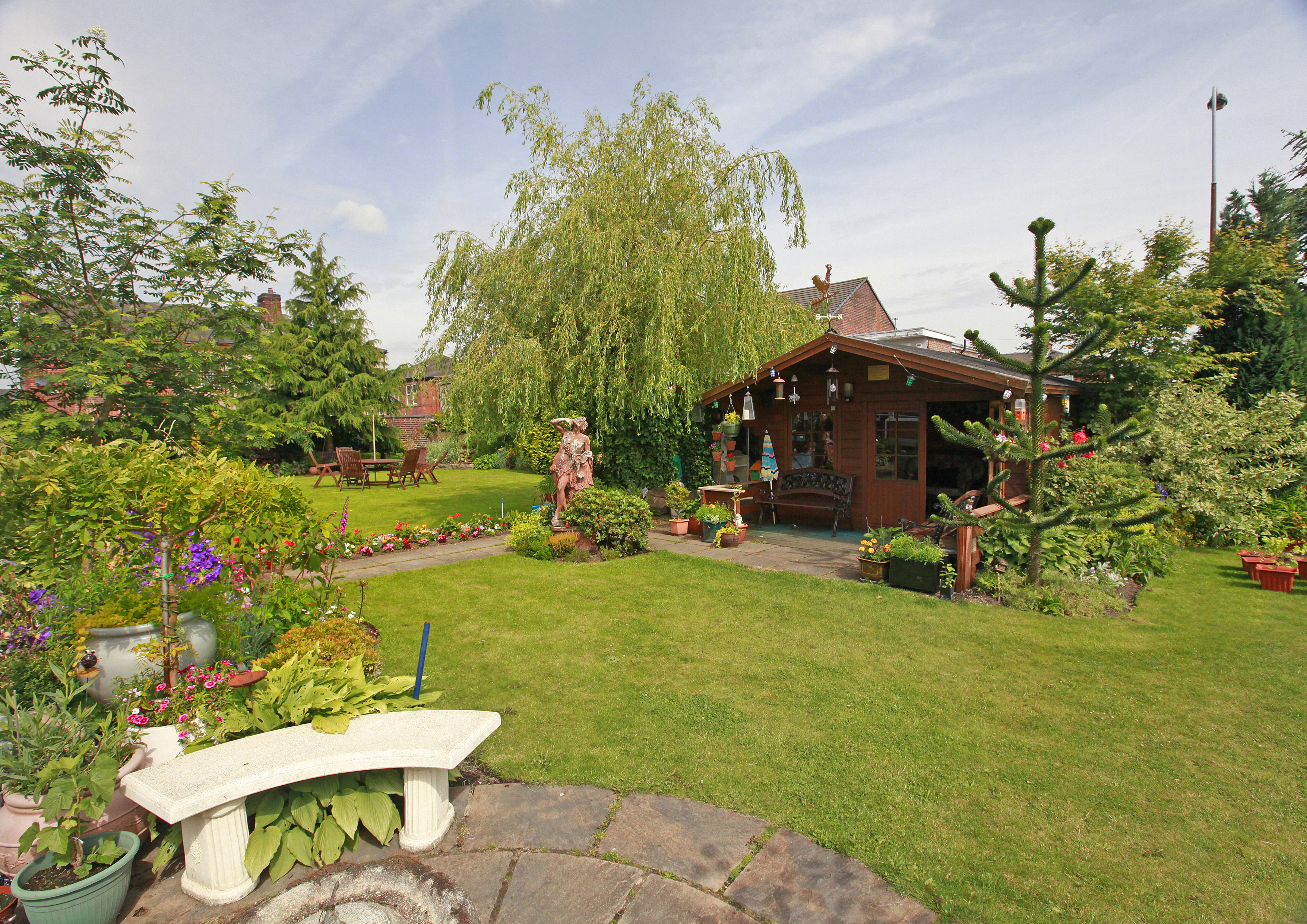 A large garden with a summer house nestled in the trees
