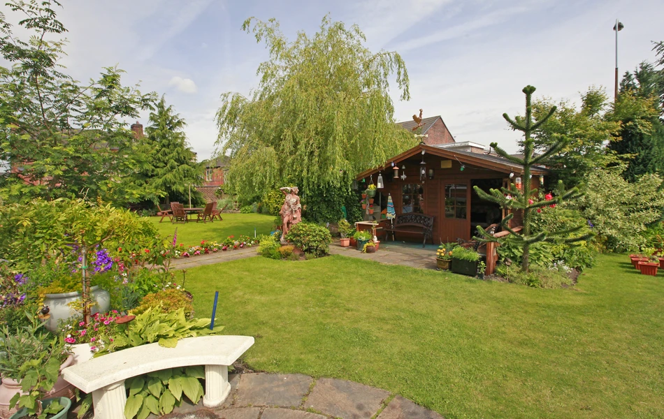 A large garden with a summer house nestled in the trees