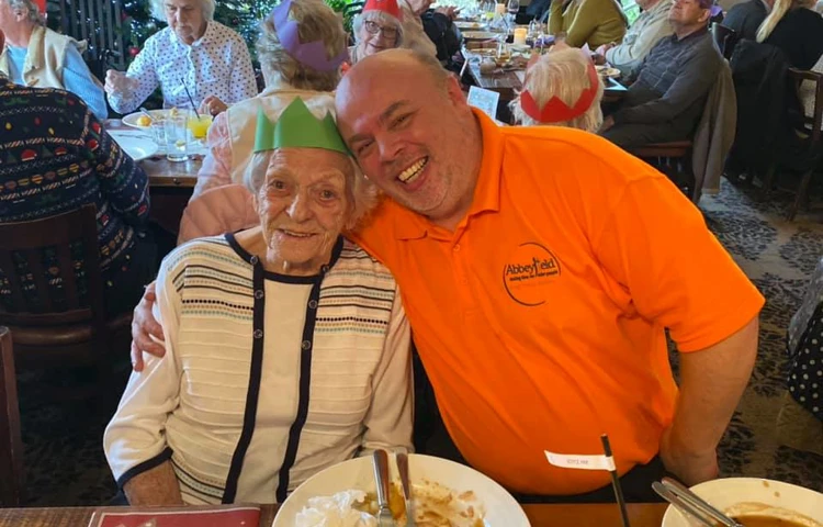 Resident and member of staff enjoying christmas dinner together at Hatch Mill