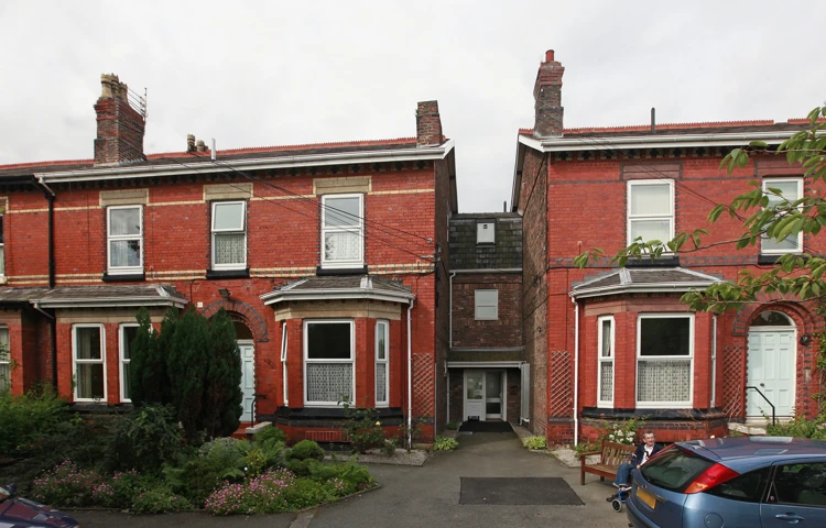 The front of Marsh House with conifers in the front garden