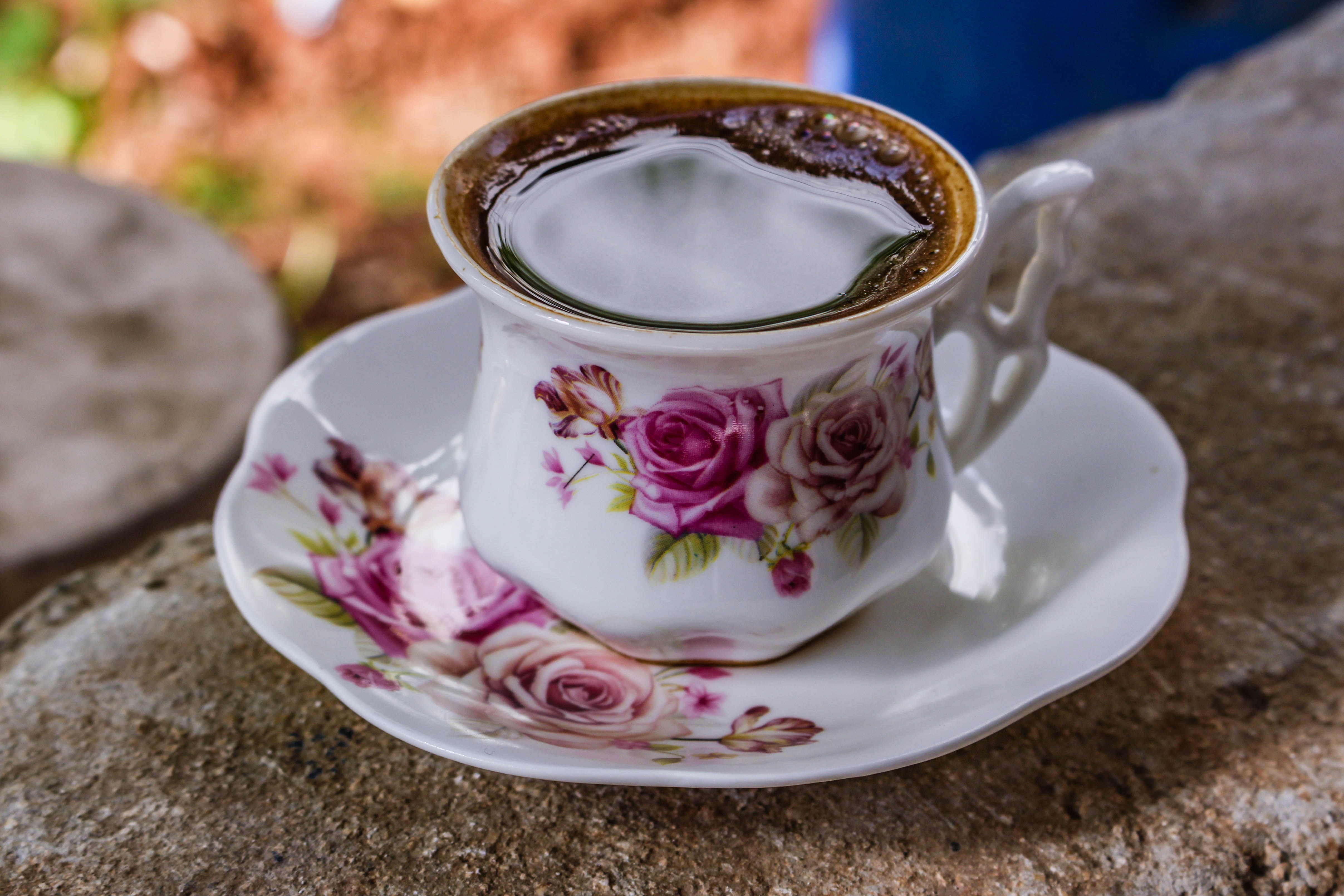 A black coffee in a a floral china teacup with matching plate