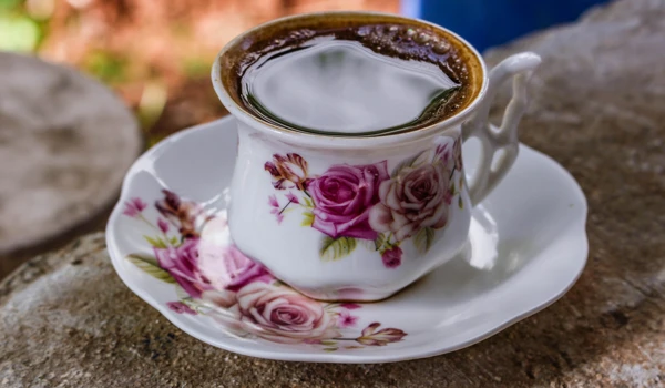 A black coffee in a a floral china teacup with matching plate