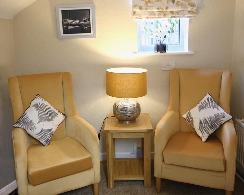 Snug area with two yellow chairs and a lit table lamp