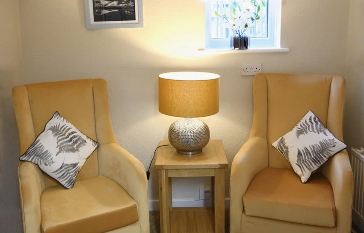 Snug area with two yellow chairs and a lit table lamp