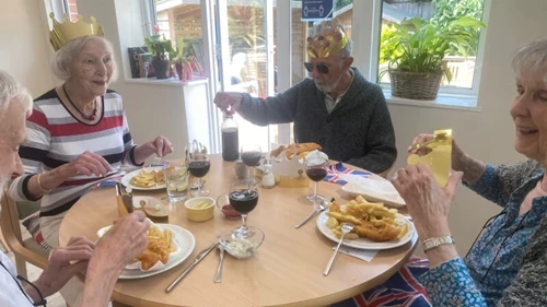 A group of people eating fish and chips at a table with gold crowns on