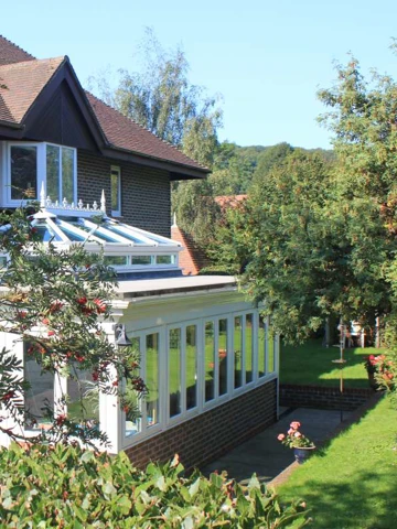 Exterior shot of the back of Abbeyfield House, Alfriston showing trees and conservatory