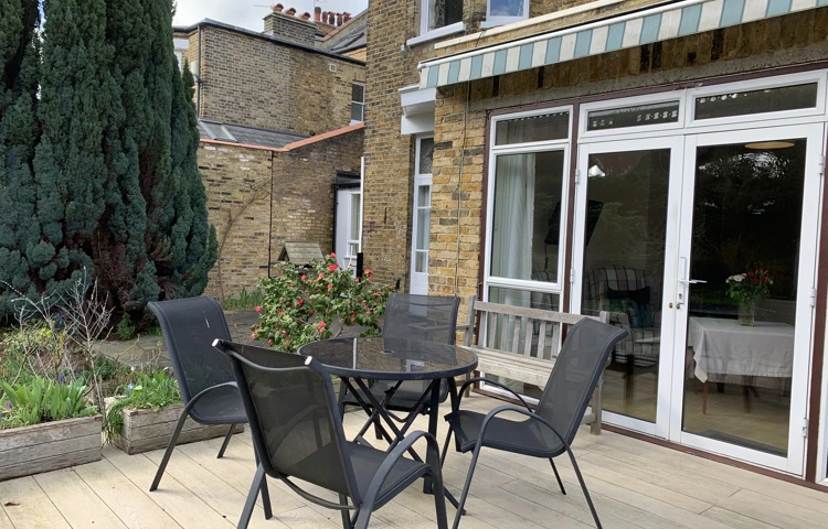 Table and chairs outside on the decking where residents can enjoy the sunshine in the garden