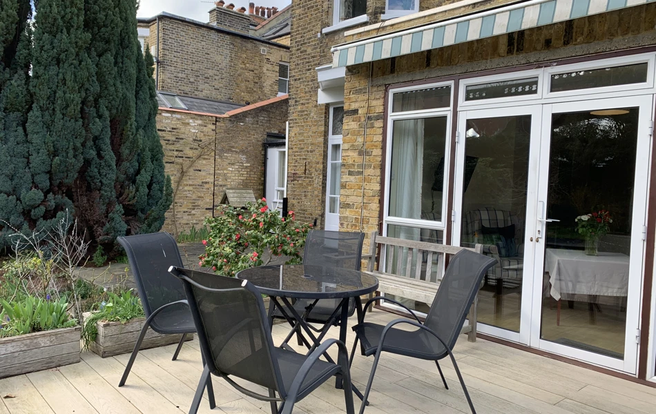Table and chairs outside on the decking where residents can enjoy the sunshine in the garden