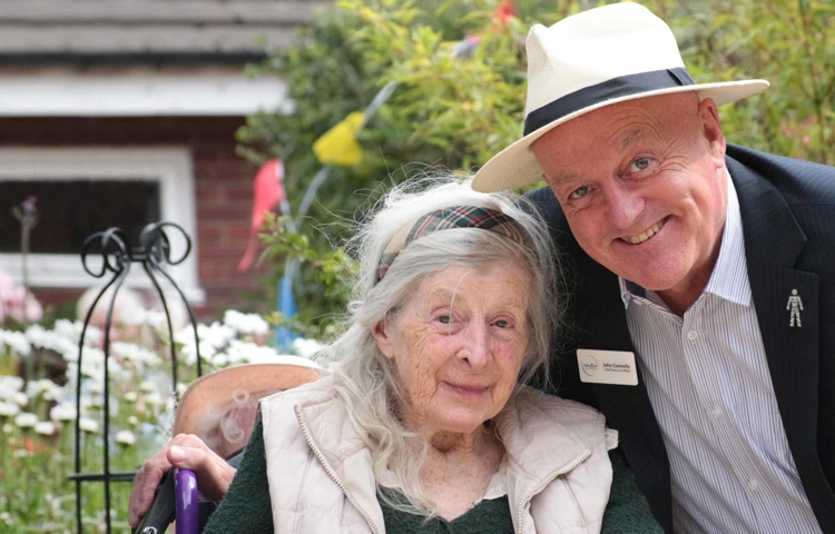 A member of staff at Abbeyfield stood in the gardens with a resident at the house