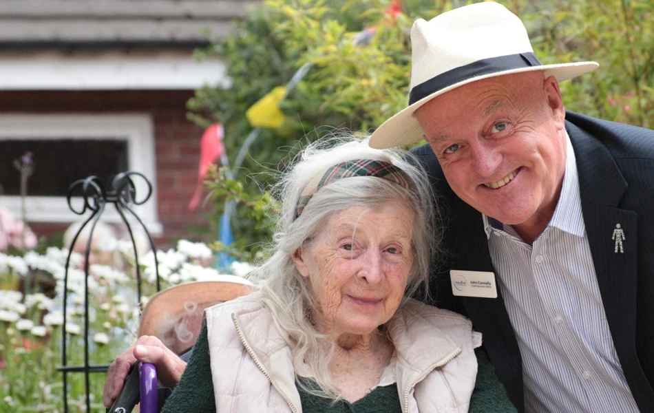 A member of staff at Abbeyfield stood in the gardens with a resident at the house