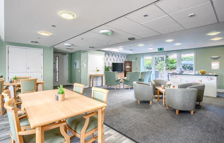 Sandwood Care Home in Nottingham offers a welcoming and stimulating community centre for residents featuring comfortable chairs, tables and a central television, perfect for socialising and activities.jpg