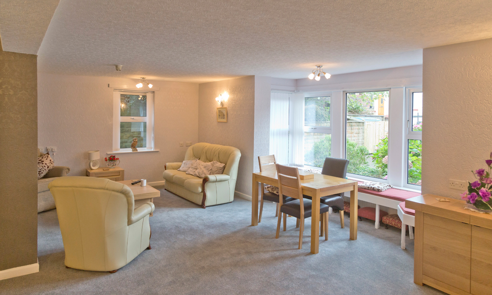 A bright cosy lounge area with seating areas for residents