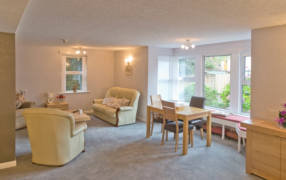 A bright cosy lounge area with seating areas for residents