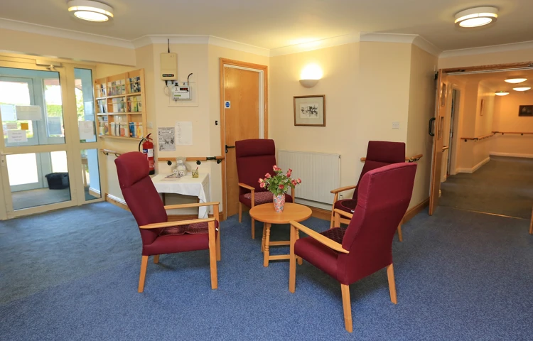 Seating area with dark red chairs and a table at Chirnside House, Lancaster