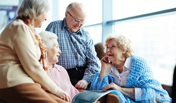Group Of Older People Sitting Together Looking Through A Book