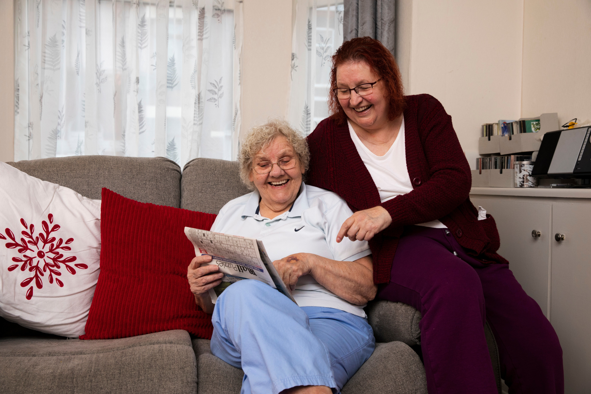 Older Woman And Woman Looking At Newspaper Together On Newspaper