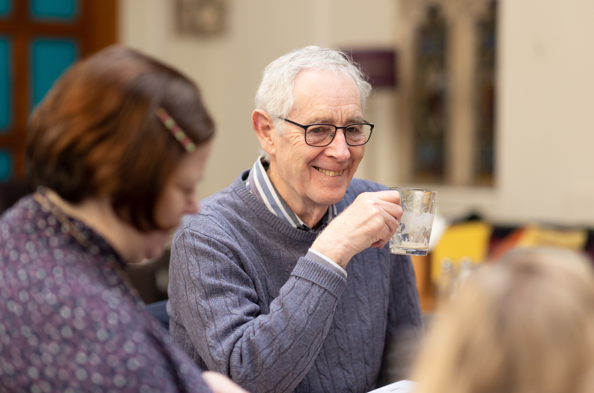 Older Man Smiling With Coffee At Table With Others