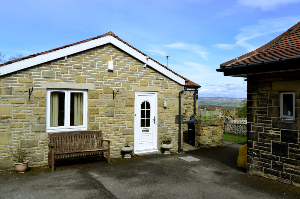 A stone bungalow with bench at Leylands Lane, Bradford BD9 5QU