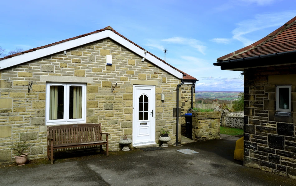 A stone bungalow with bench at Leylands Lane, Bradford BD9 5QU