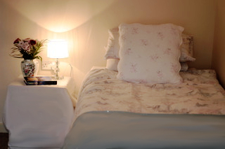 A bedroom with a lamp and flowers on the bedside table