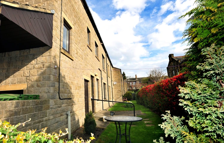 The rear of Abbeyfield House with a table in the garden, independent living in Pudsey