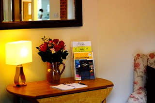 A side table with a lamp and flowers in a vase