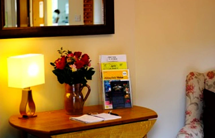 A side table with a lamp and flowers in a vase