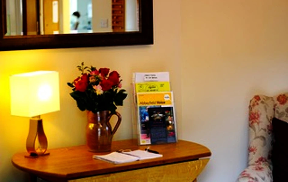 A side table with a lamp and flowers in a vase