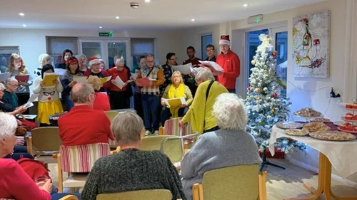 A group singing christmas carols in the residents lounge