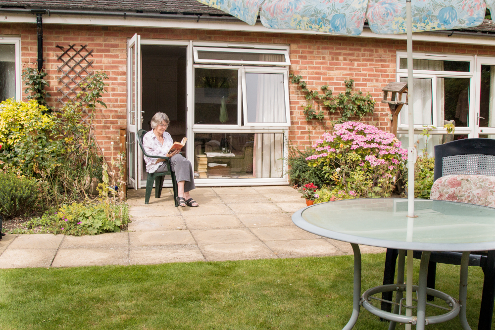 Resident sitting on the patio reading a book in the sunshine at Westgate