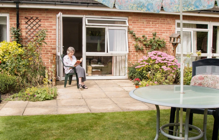 Resident sitting on the patio reading a book in the sunshine at Westgate