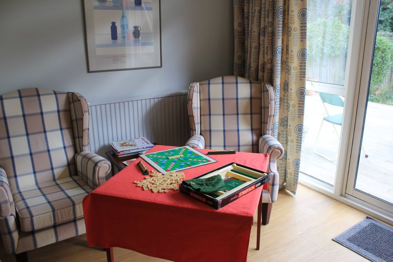 Armchairs by the window with a game of scrabble set up for residents to play together