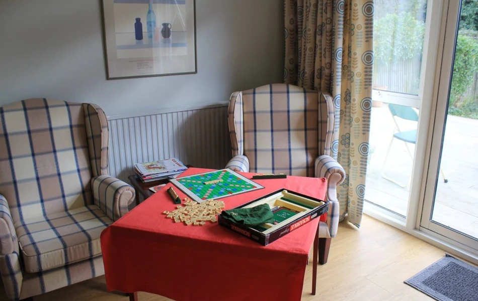 Armchairs by the window with a game of scrabble set up for residents to play together
