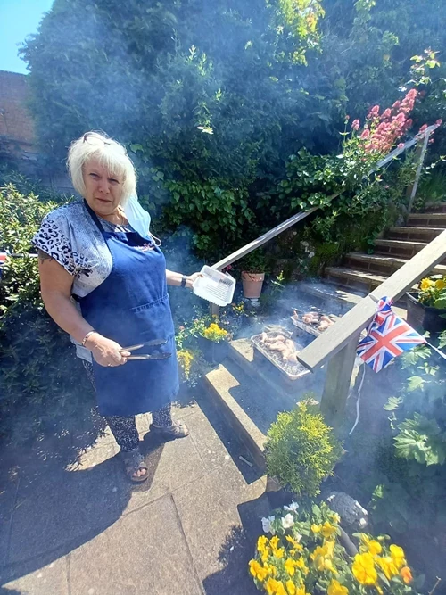 Staff member in a pinney with tongs and tupperware