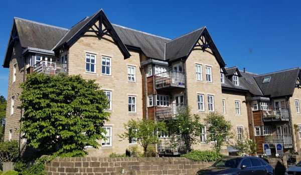 The outside of the house with blue skies surrounded by a stone wall