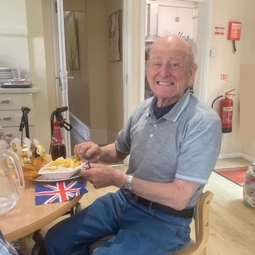 An older man with fish and chips, smiling