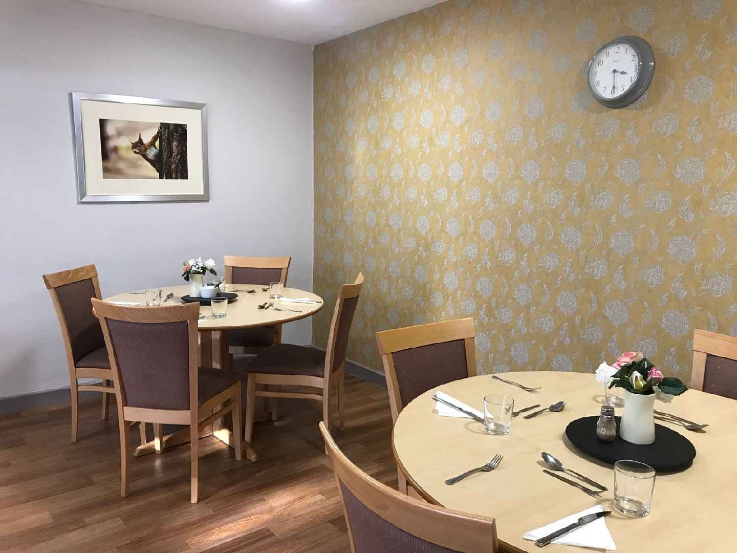 The dining area with table and chairs and yellow flowered wall
