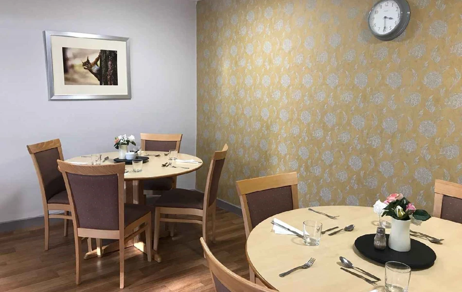 The dining area with table and chairs and yellow flowered wall