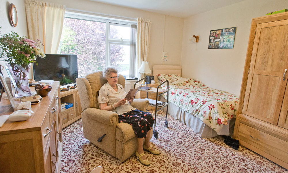 A resident is sat reading in her bedroom
