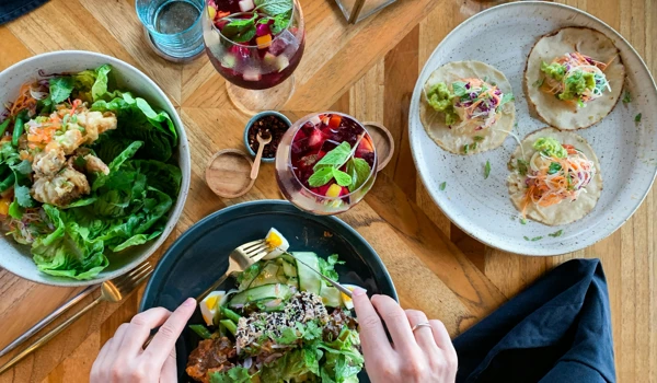 People Tucking Into Some Health Meals On Wooden Table